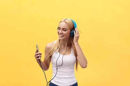生活风格的肖像一个快乐的女人用耳机监听音乐在黄色图片