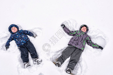 两个小兄弟姐妹孩子穿着五颜六色的冬装做雪天使图片