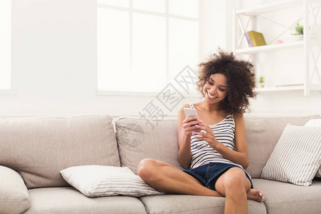 年轻黑人女在家里智能手机上传递信息图片