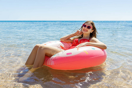 快乐的年轻女孩在海面上喷洒甜圈夏天图片
