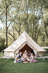 快乐的家庭穿着时髦的布霍散装衣正在一起享受时光坐在花园外户的大帐篷顶尖假发图片
