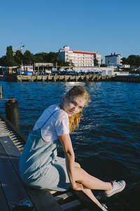 坐在码头的年轻金发女孩少女在海边放松图片