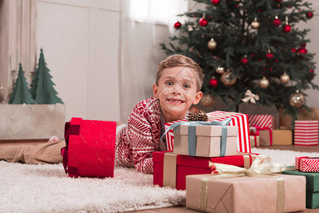 快乐的男孩躺在地板上与圣诞节礼物背景图片
