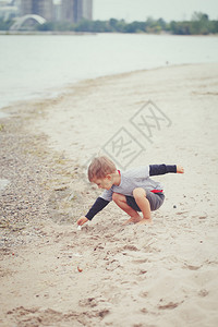 沙海湖洋河海滩上的一个小孩蹒跚学步的男孩寻找有趣的东西图片