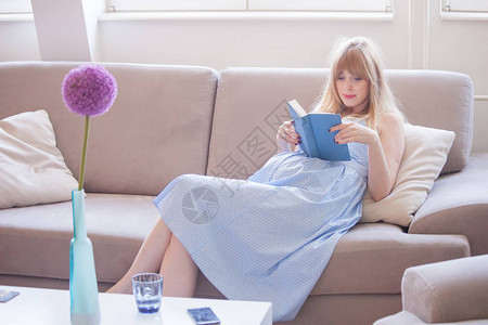 年轻怀孕妇女坐在公寓里看书图片