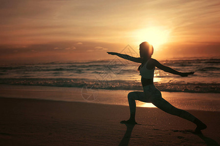 在海滩做瑜伽练习的运动型年轻女健康生活理念和身心发图片