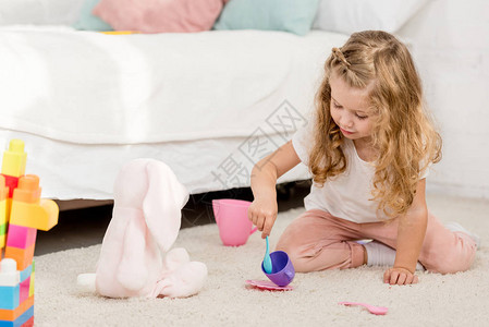 在儿童房间里玩兔子玩具和塑料杯的可爱幼稚图片