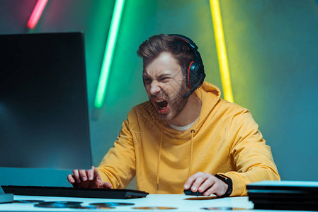 用电脑鼠标和键盘玩电子游戏的耳机上发着愤怒和帅图片