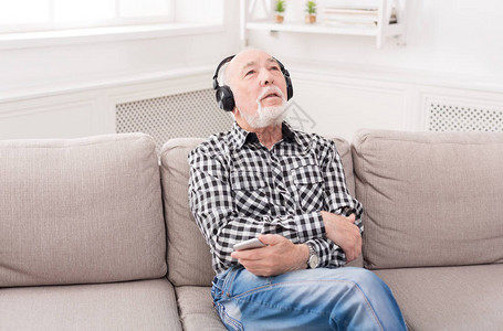 老人用耳机在智能手机上听音乐图片
