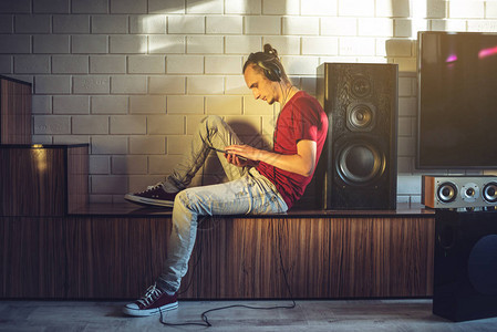 一个音乐爱好者用耳机和手机在现代室内听音乐图片