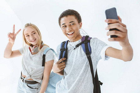 多元文化青少年在智能手机上自拍的肖图片