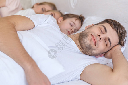 一起睡在床上的年轻家庭图片