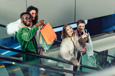 在购物中心的自动扶梯上的年轻时尚购物者群体图片