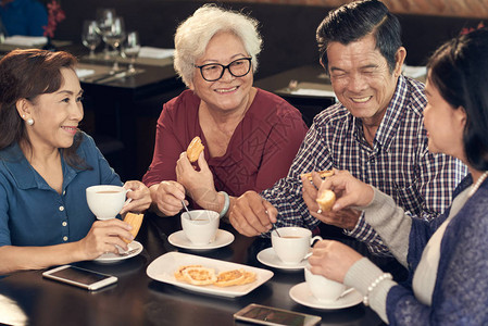 退休的亚洲朋友在咖啡馆吃早餐喝茶图片