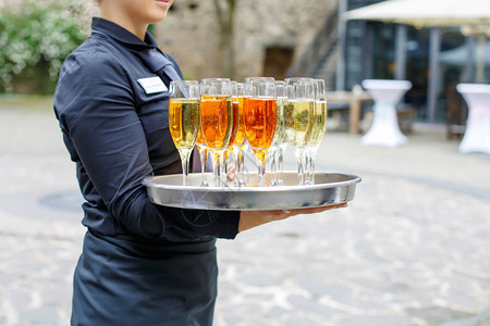 盛装香槟和酒杯的女服务员在夏季户外图片