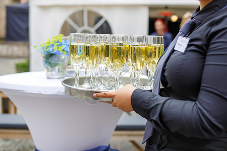 盛装香槟和酒杯的女服务员在夏季户外图片