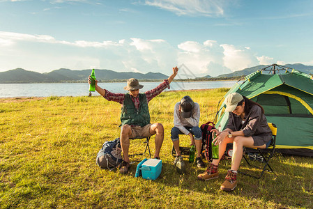 醉酒的游客在草地上露营和野餐时参加派对山和湖背景人和生活方式的概念户外活动和休闲主题背包客和徒图片