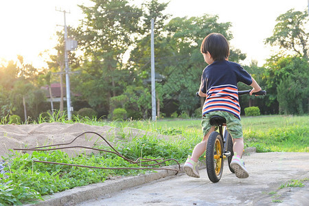 可爱的男孩在公园玩平衡自行车在早晨阳光图片