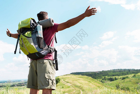 旅游者背着包站在夏日草地上用伸展的手站图片