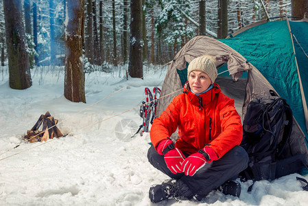旅游妇女坐在冬季森林的帐篷附近图片