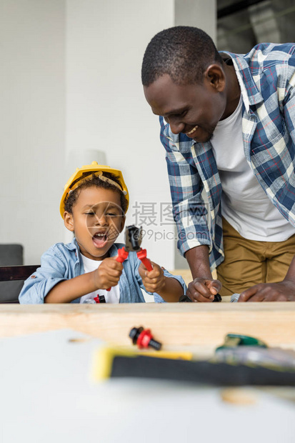 非裔美国父亲和可爱的儿子在家里玩工具游戏图片