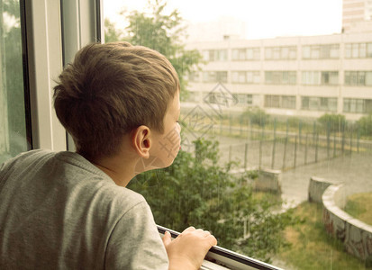 透过窗户看的男孩透过窗户看雨的男孩背景图片