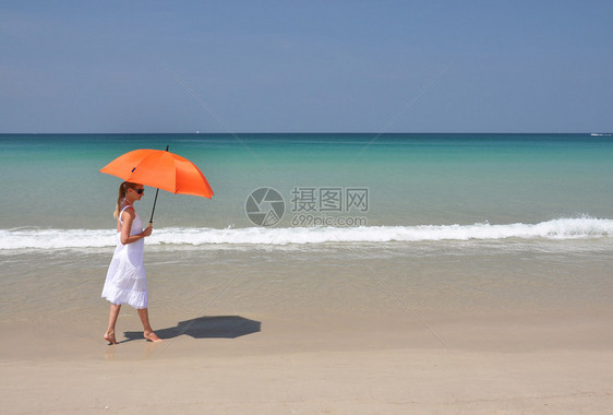 沙滩上打着橙色雨伞的女孩图片