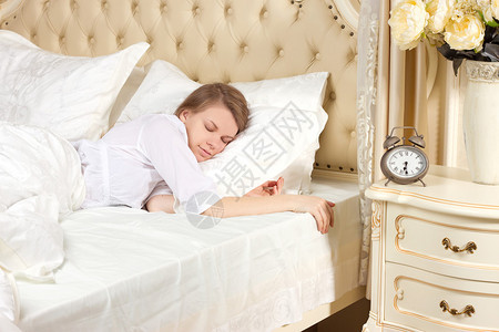 美丽的睡着女人休息在床上带着闹钟准备图片