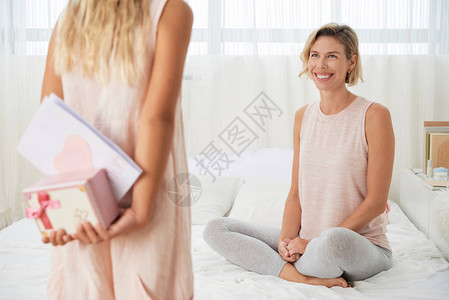 微笑的女人在床上女儿拿着礼图片