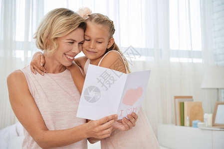 快乐的母亲读小女儿的贺卡图片