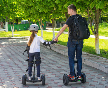 年轻父亲和女儿在公园乘坐电动小型停背景图片