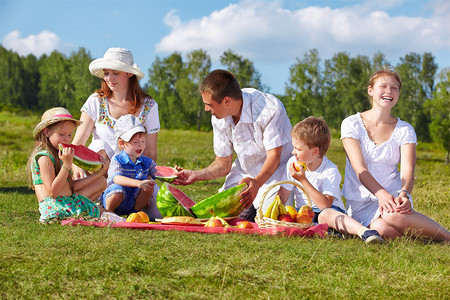 欢乐家庭在公园绿草地野餐享受西瓜的图片