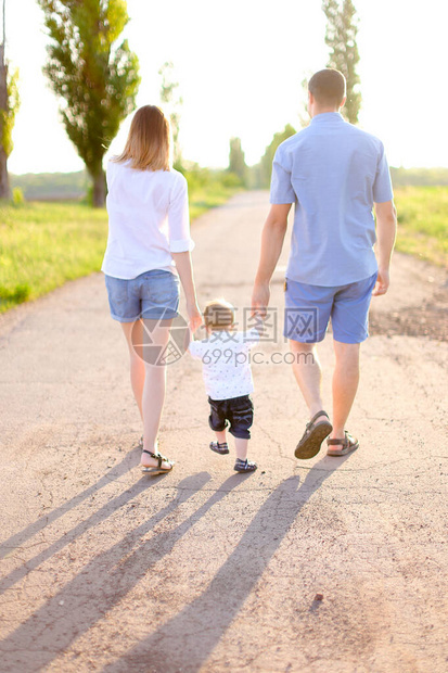 年轻的父母带着小婴儿走在路上的背影图片