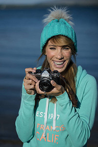 微笑的年轻女人使用相机拍照图片