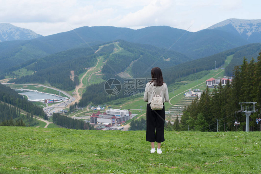 女孩背着包站在山丘上欣赏山峰图片