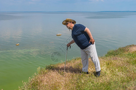 穿着蓝色T恤和短裤的单身老人站在Dnipro河高拔的河背景图片