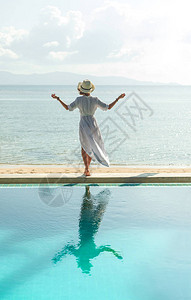 女孩站在游泳池边看海的背影图片