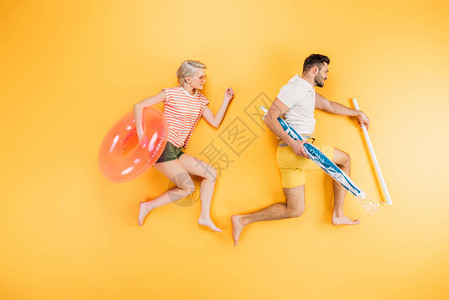 带着沙滩伞和游泳环的快乐小情侣在黄图片