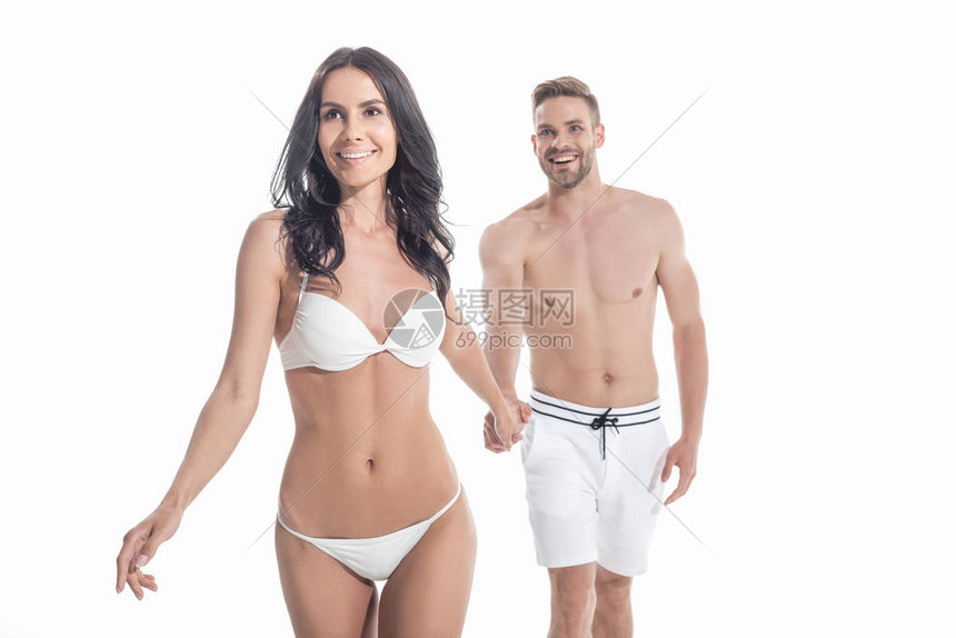 穿着泳装的一对漂亮的夫妇手牵走路在白图片