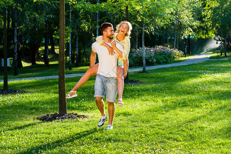 在公园里玩耍情人享受约会浪漫游戏男人背着那图片