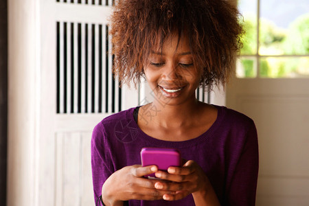 一个微笑着的非洲年轻女看着手机图片