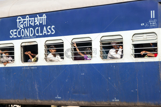 身份不明的乘客在2012年10日在印度斋浦尔的移动印度铁路列车的窗户上挂着印度铁路每年运送约图片