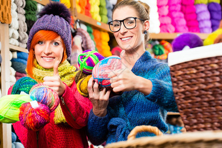 年轻妇女在编织时装店购买彩色羊毛和纱布图片