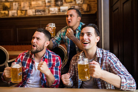 三个男人在酒吧一起喝啤酒和玩乐图片