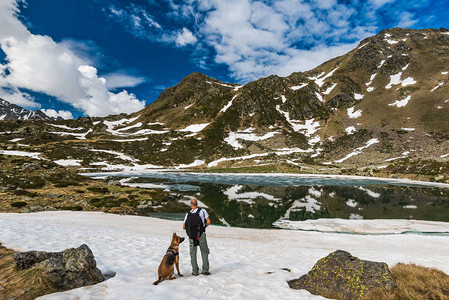 与狗一起在比雷牛斯接受试验的积极徒步者站在雪图片