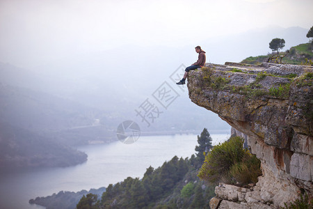 坐在悬崖边缘的年轻人看图片