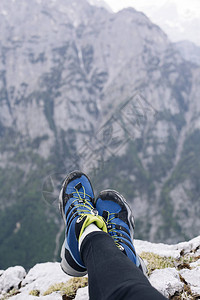 悬崖边上的女徒步旅行者鞋高地在下面的山上图片