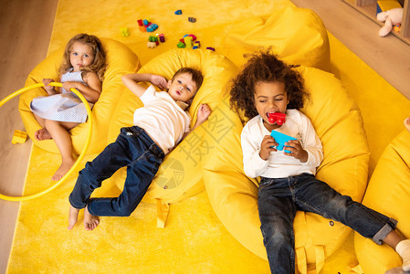 多族裔儿童坐在幼稚园玩具的豆袋椅上图片