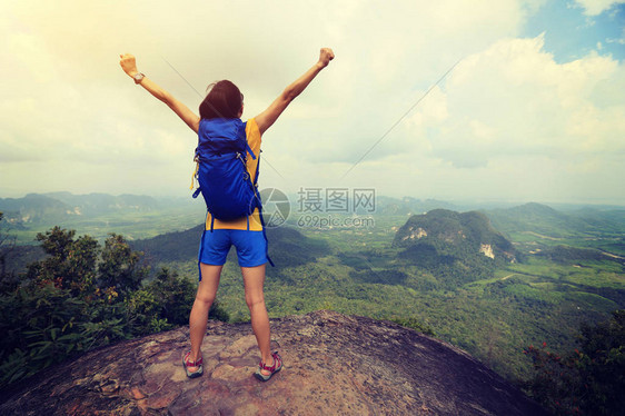 举手站在山峰上的年轻女子图片