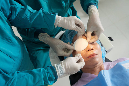 外科医生在手术后对成熟亚洲病人的眼睛施用贴图片